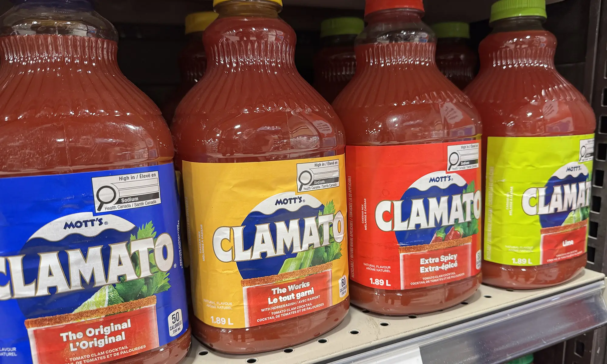 Bouteilles de Clamato au supermarché affichant le symbole nutritionnel canadien pour une teneur élevée en sodium.