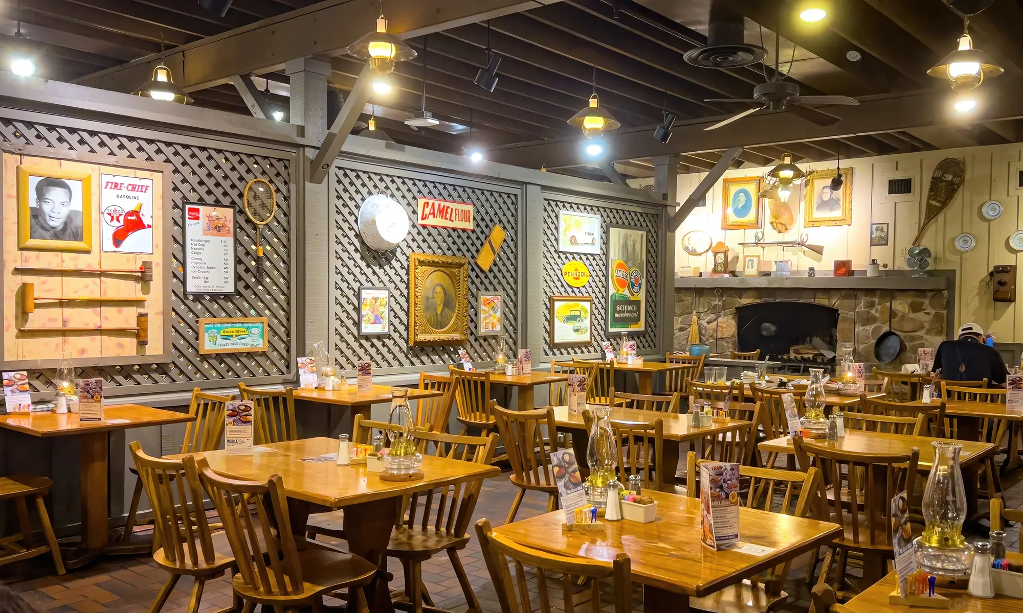 Intérieur d’un restaurant Cracker Barrel avec tables en bois, murs décorés d’objets rétro et grande cheminée en pierre.